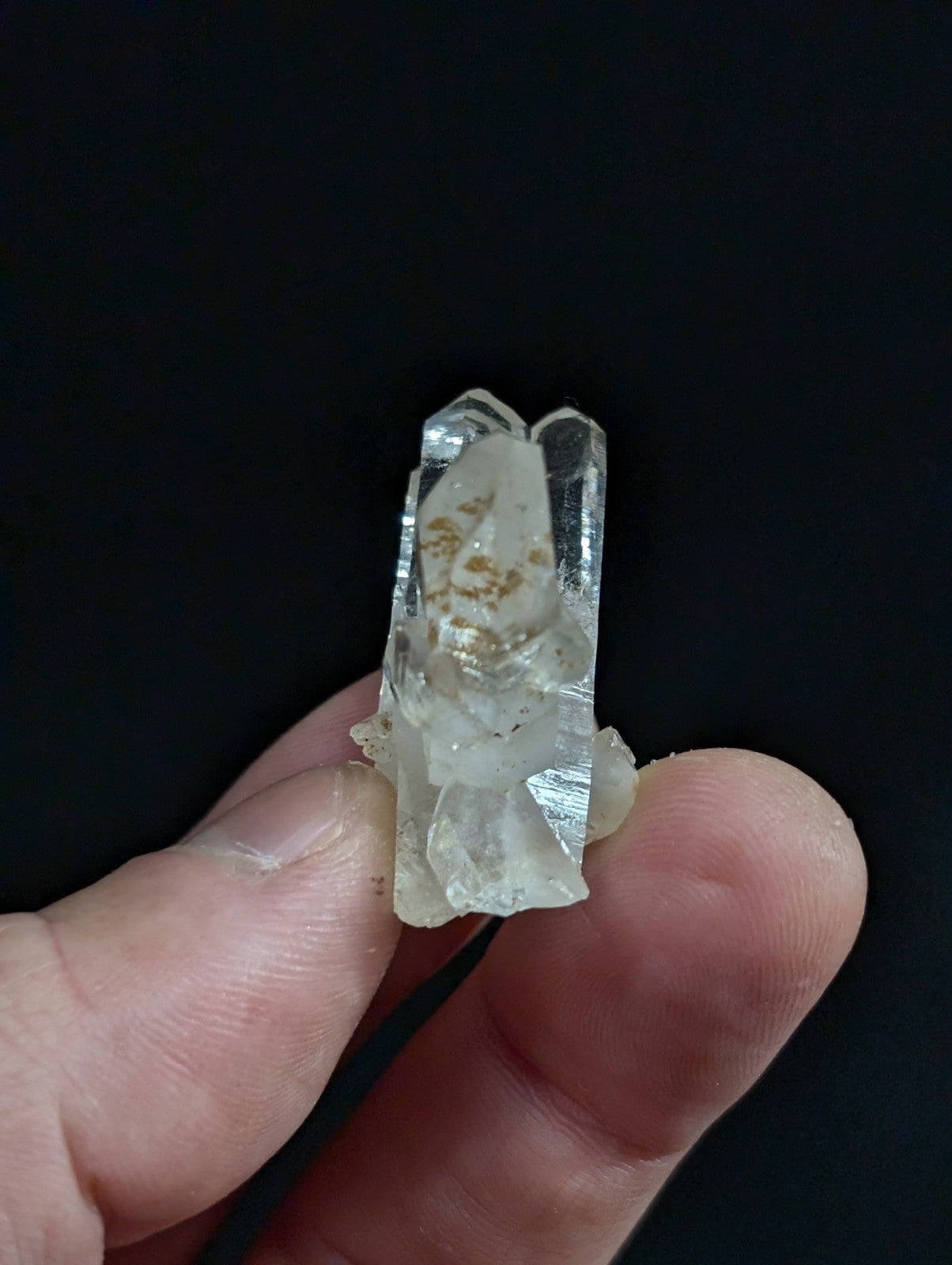 A translucent, clear quartz crystal with natural inclusions and a faceted top.