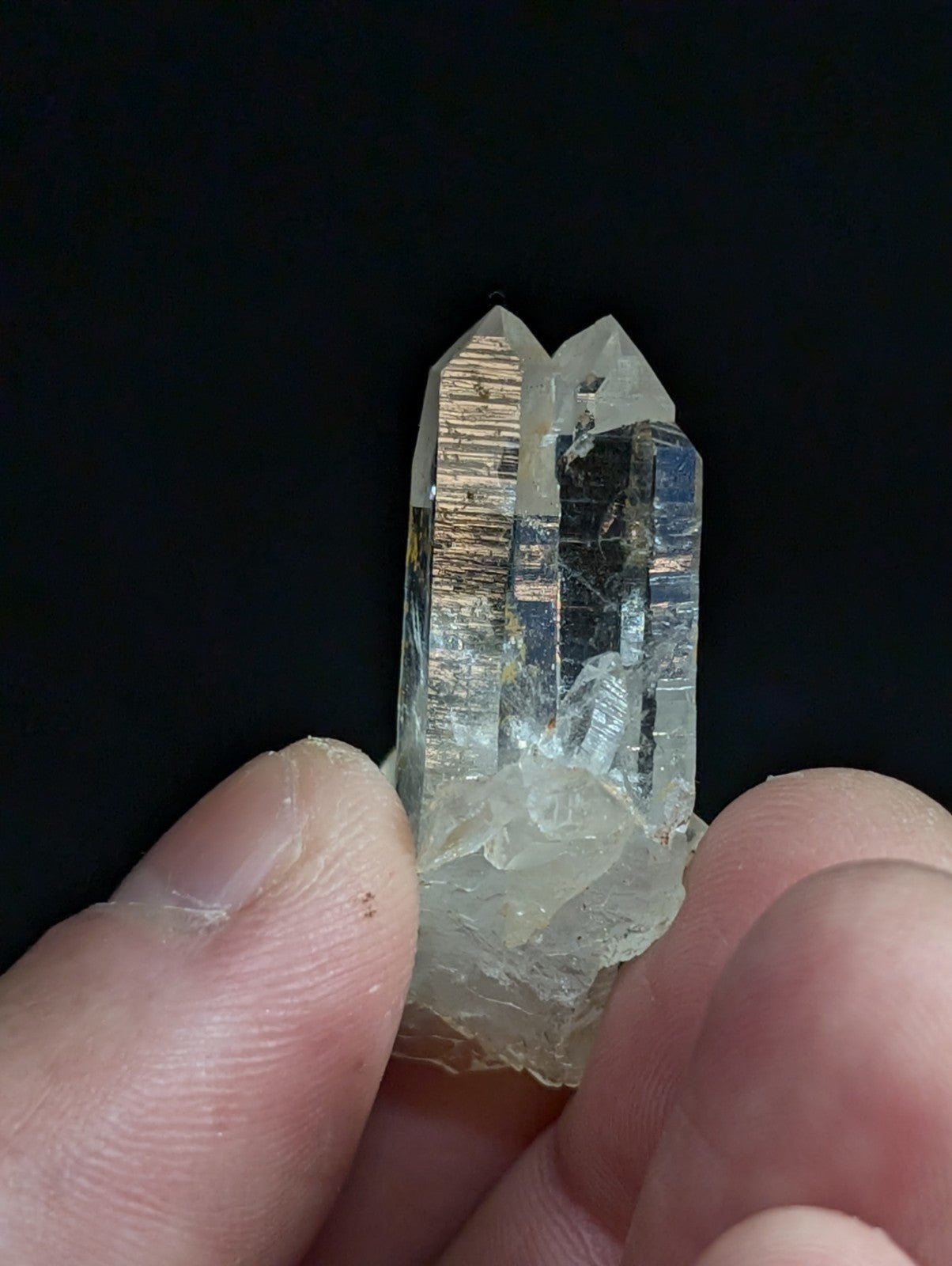 A clear quartz crystal cluster with a dual-pointed, transparent structure and subtle golden inclusions.