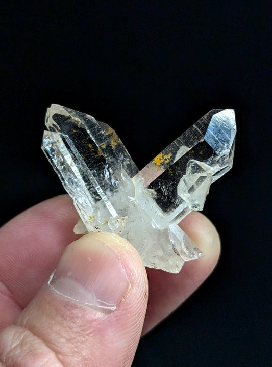 A clear quartz crystal cluster with sharp, faceted points and subtle golden inclusions.