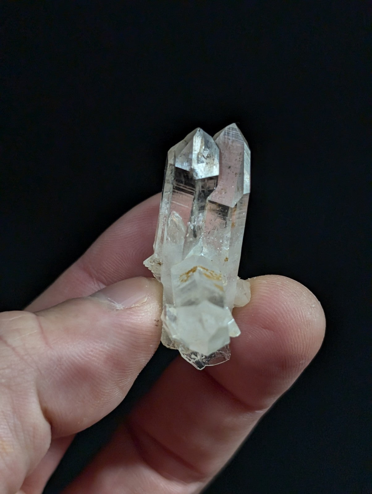A clear quartz crystal cluster with two prominent, faceted points and a base of smaller crystals.
