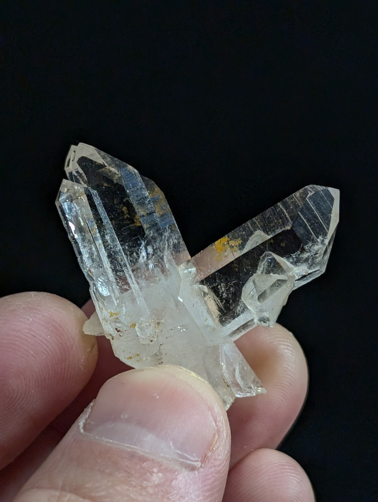 A clear quartz crystal cluster with translucent, faceted points and subtle golden inclusions.