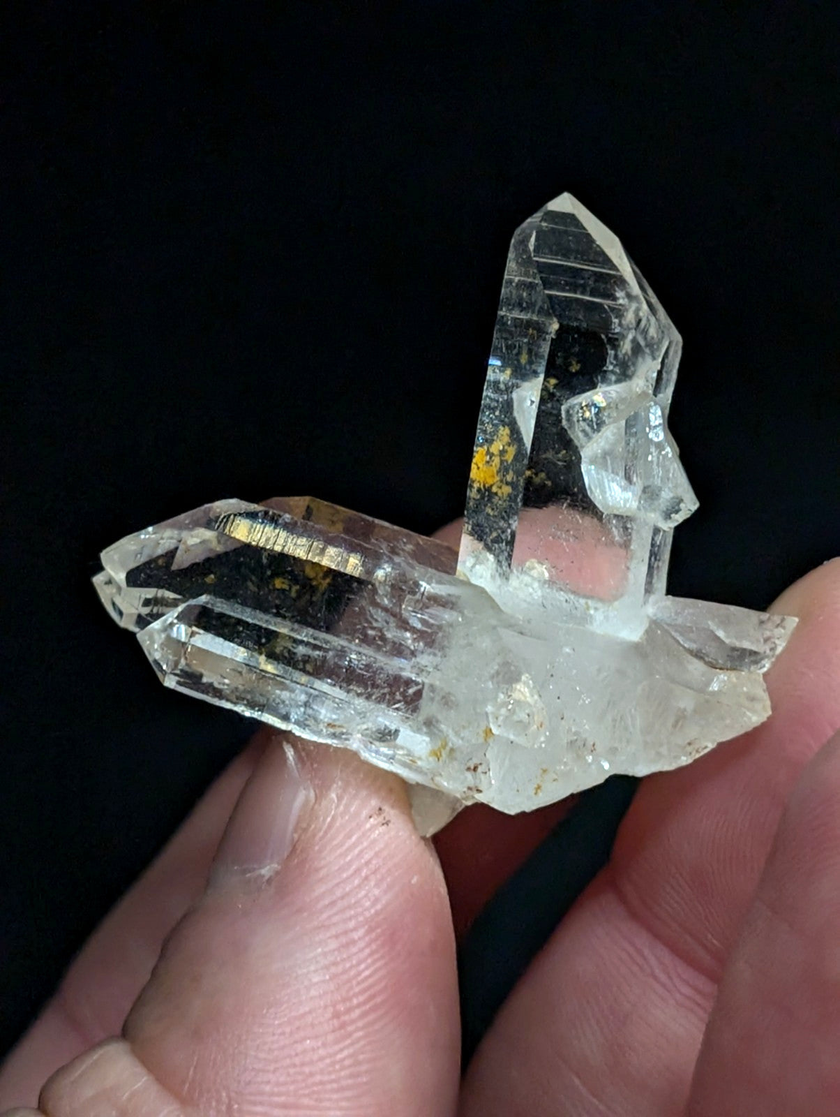 A clear quartz crystal cluster with sharp, faceted points and subtle golden inclusions.