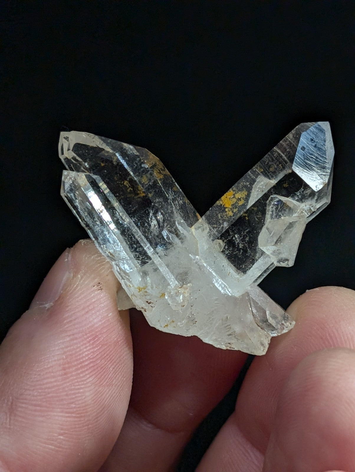 A clear quartz crystal cluster with sharp, faceted points and subtle golden inclusions.