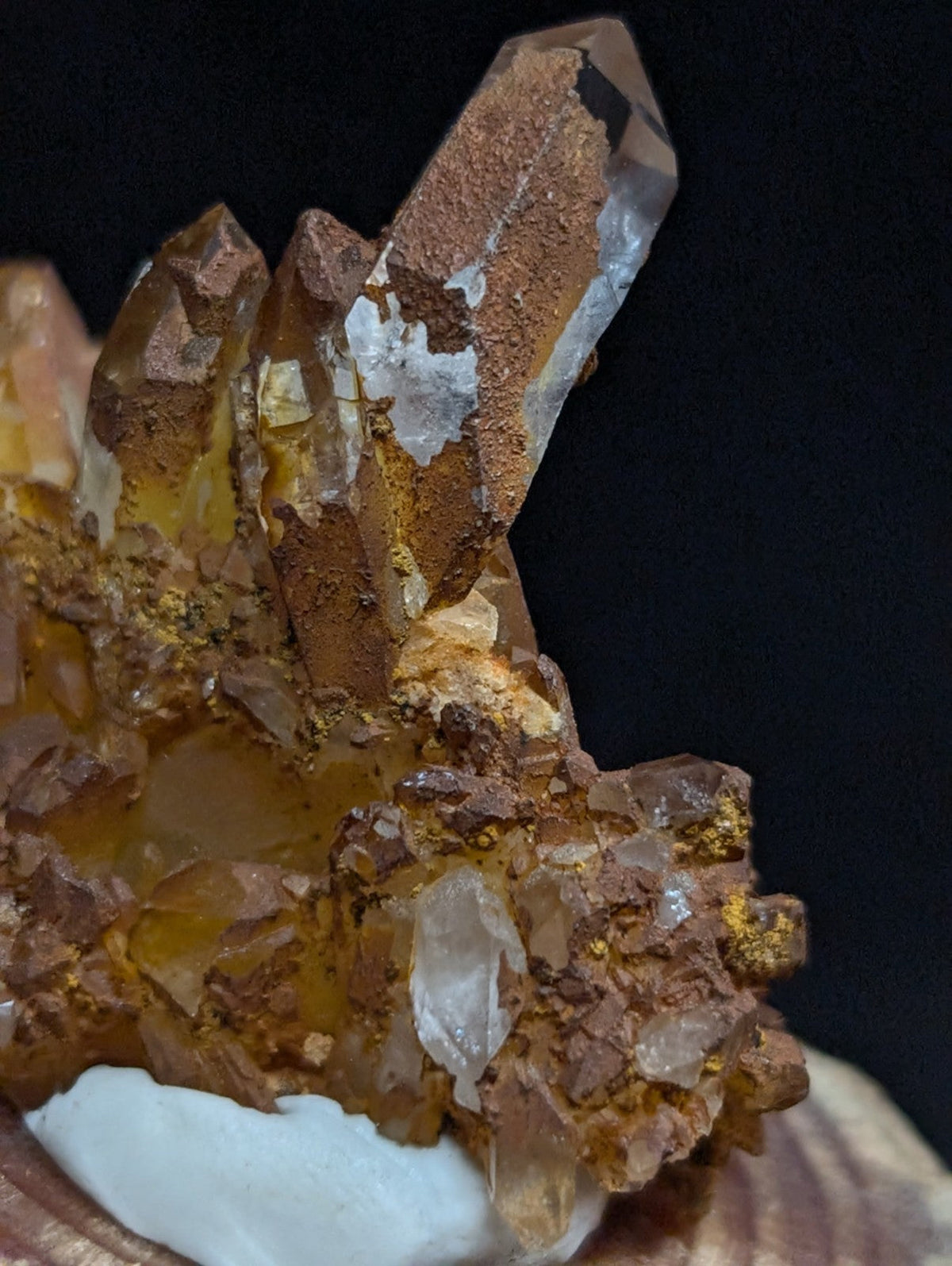 A cluster of translucent amber and clear quartz crystals with golden mineral inclusions, set against a dark background.