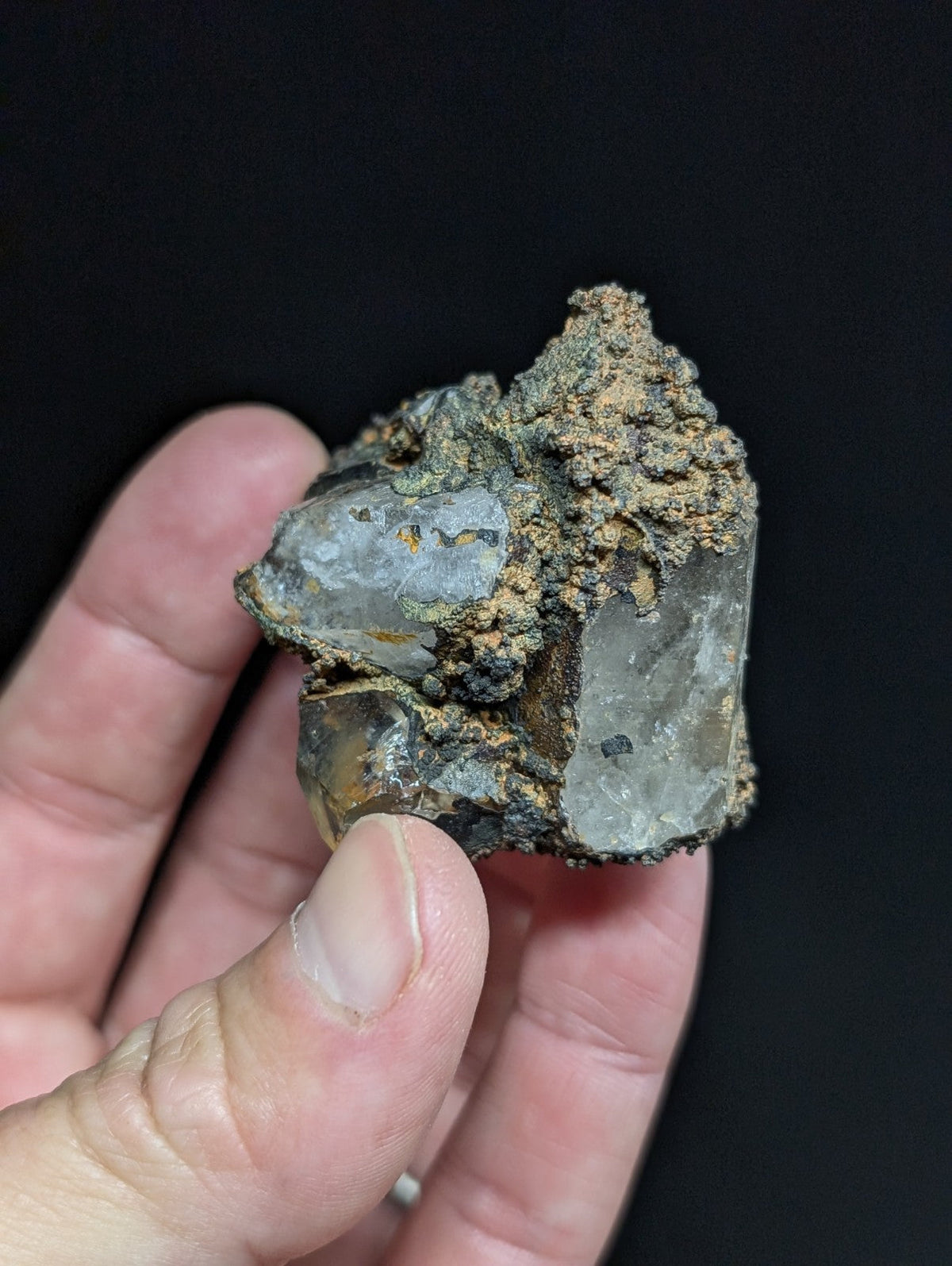 A rough, translucent quartz crystal with a grayish hue and patches of brownish mineral matrix.