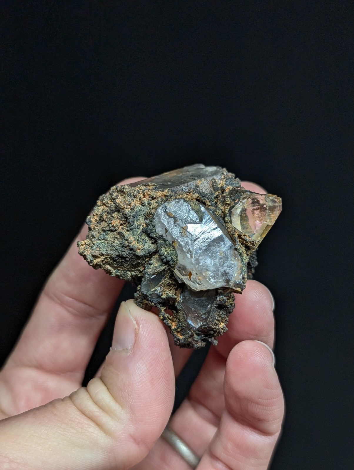 A translucent, faceted quartz crystal embedded in a rough, earthy matrix.