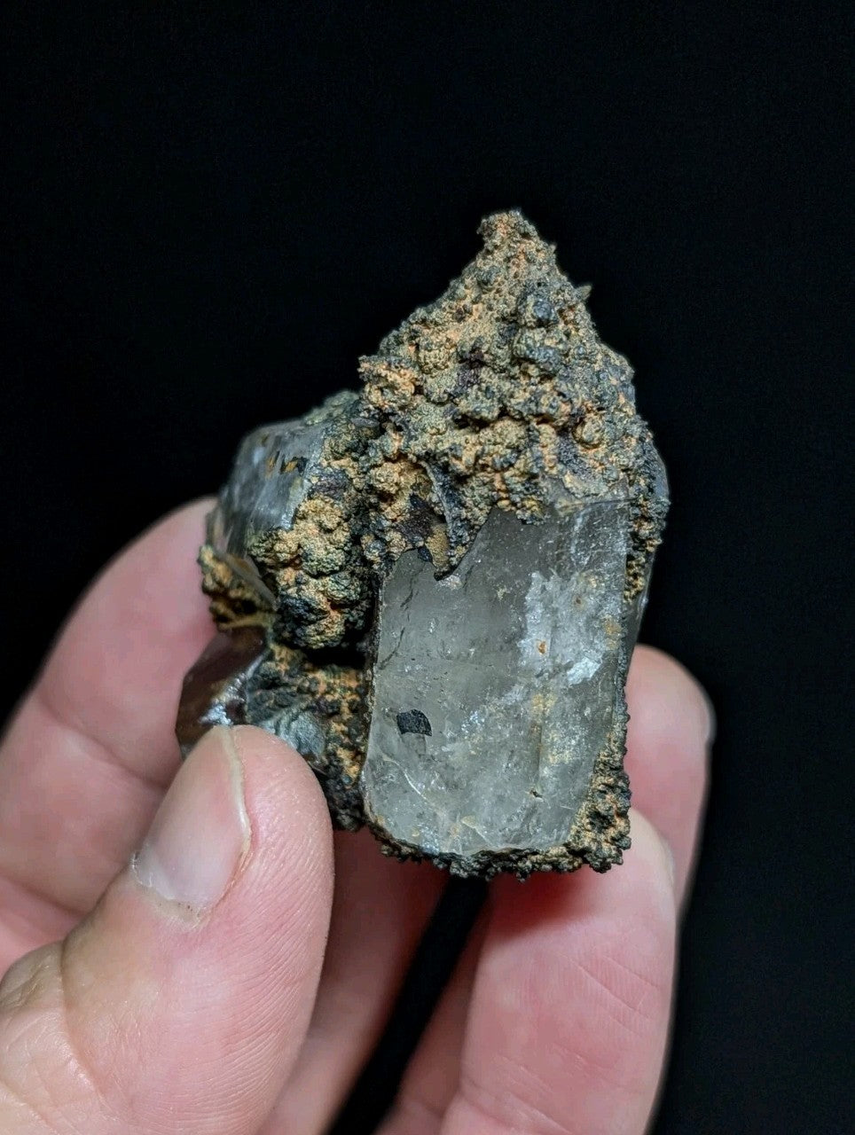 A translucent, grayish quartz crystal with rough, earthy matrix surrounding it.