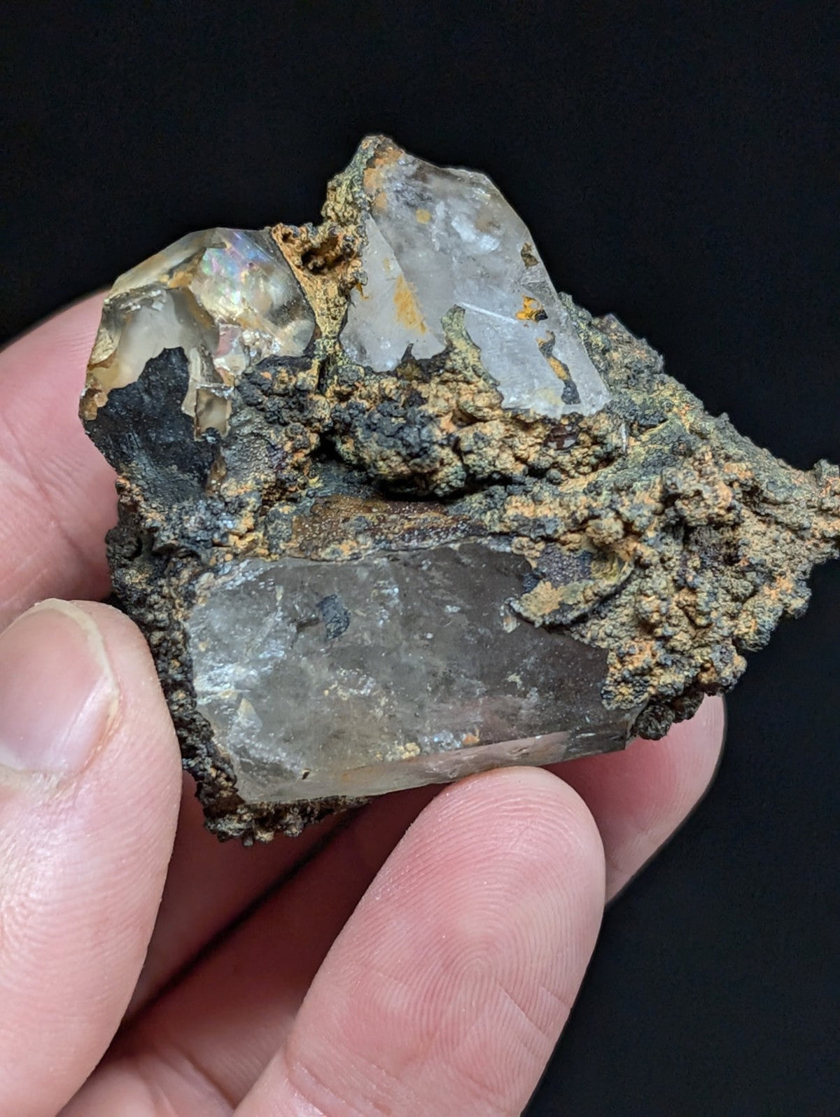 A translucent, multi-faceted quartz crystal cluster with earthy brown and black matrix material.