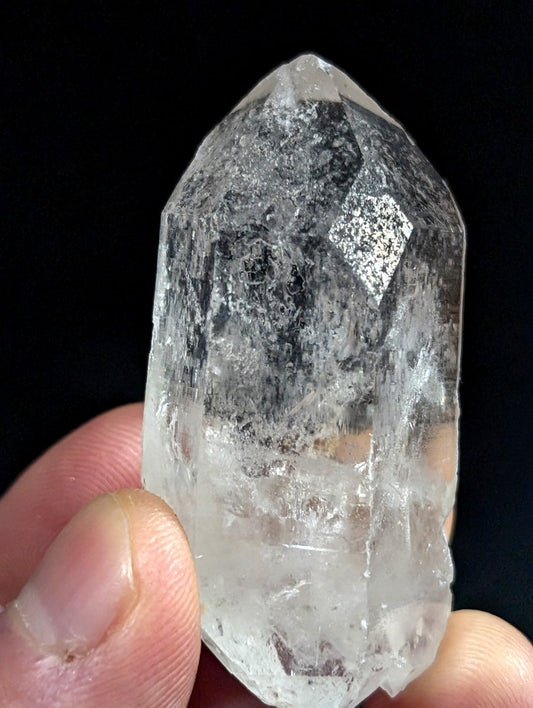 A translucent, clear quartz crystal with a pointed tip and visible internal inclusions.