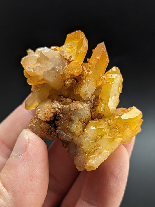 A cluster of translucent golden-yellow quartz crystals with sharp, faceted points and a mix of clear and amber-hued sections.