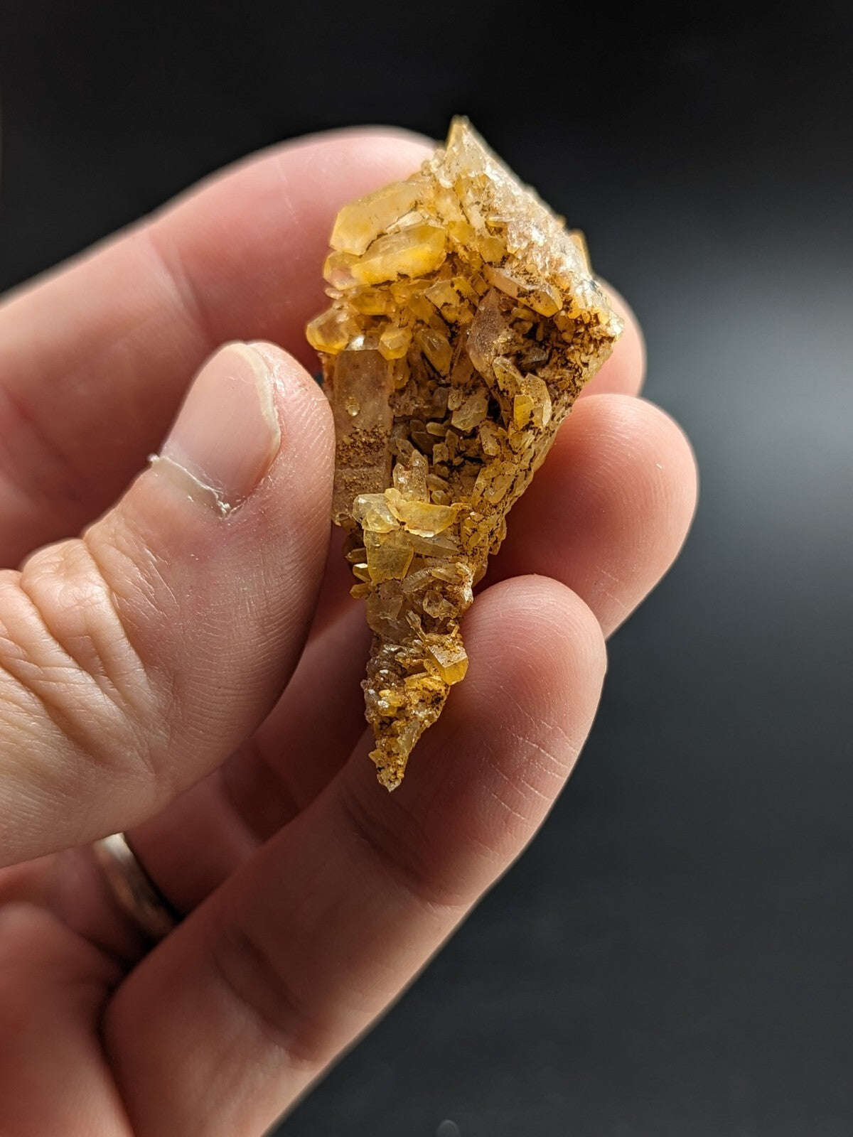 A translucent golden-yellow crystal cluster with jagged, faceted surfaces and a rough, earthy base.