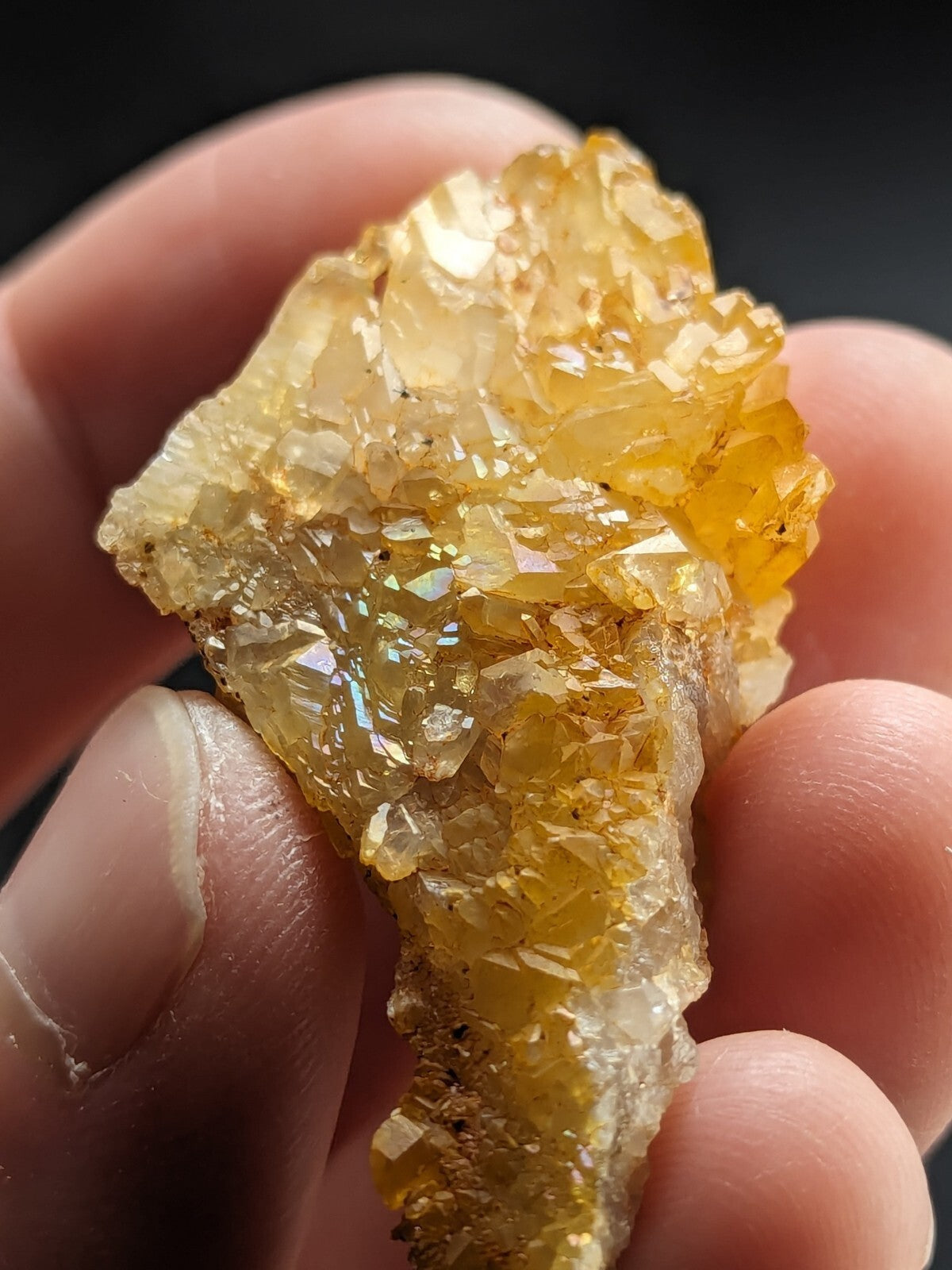 A translucent golden-yellow crystal cluster with faceted, interlocking formations held gently in a hand.
