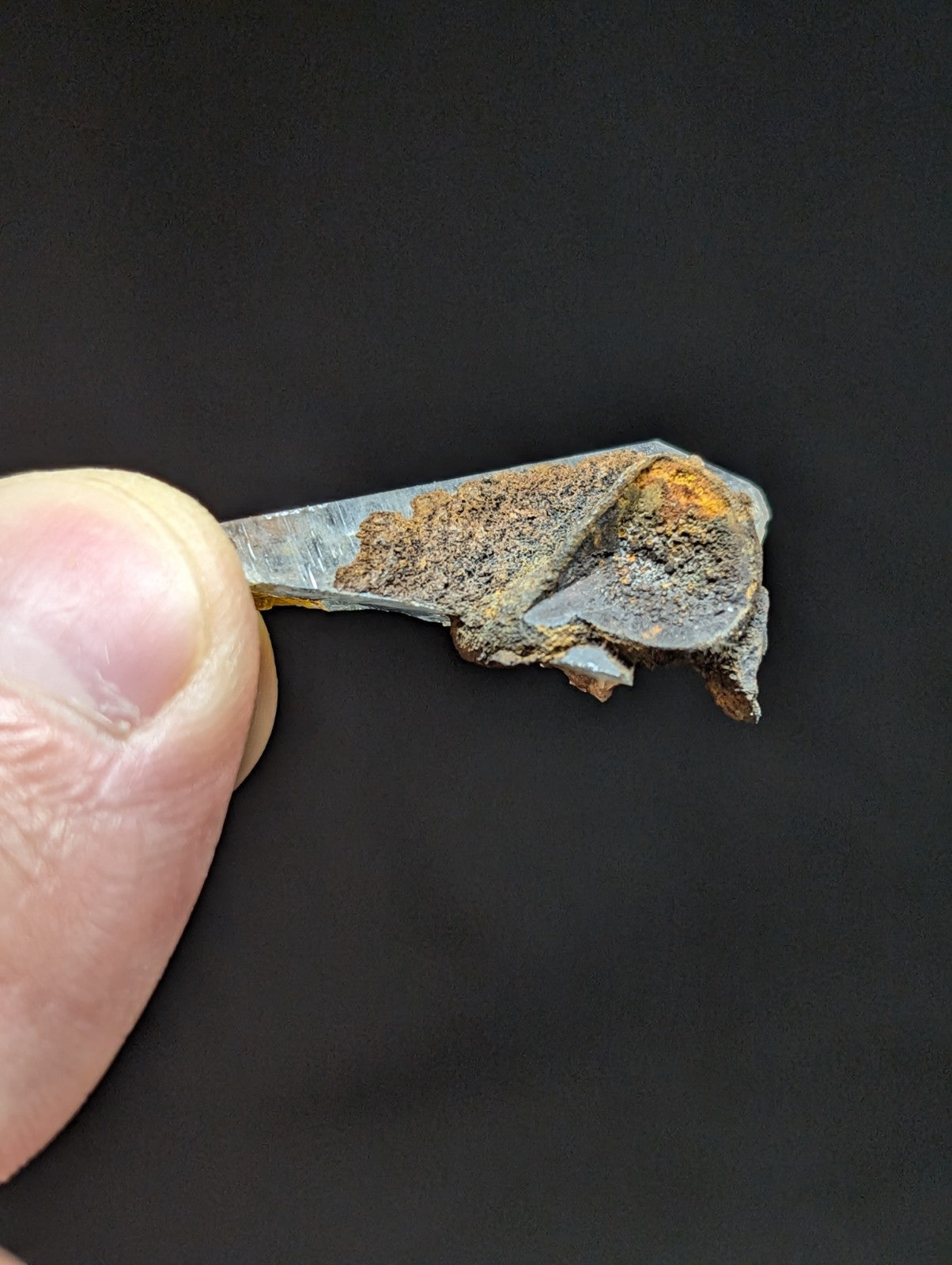 A corroded, rusted metal fragment with a jagged edge and uneven surface.