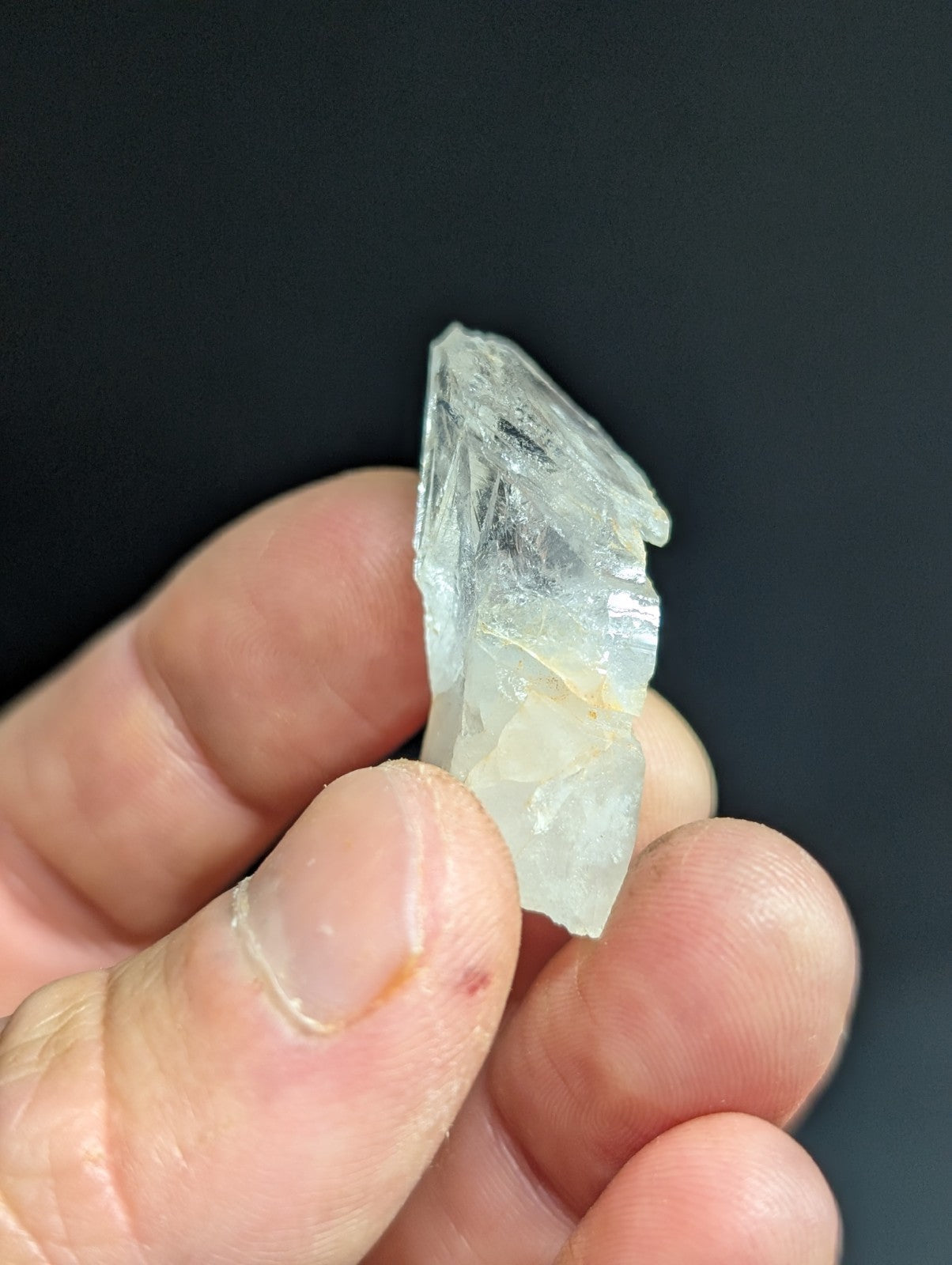 A translucent, pale blue crystal with jagged edges and a rough, natural surface.