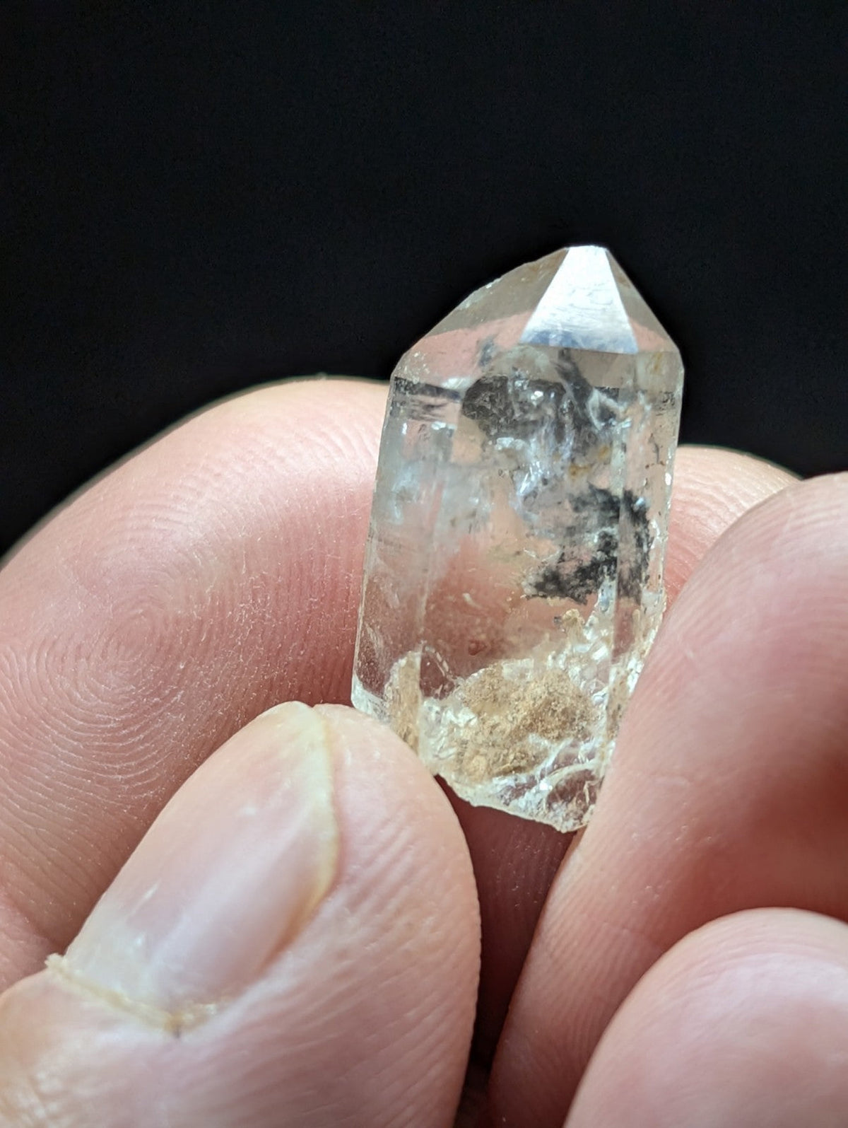 A clear, faceted quartz crystal with natural inclusions and a pointed tip.
