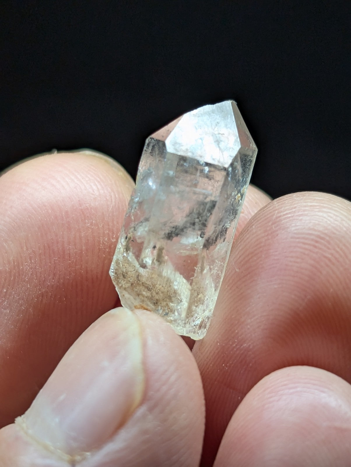 A clear, translucent quartz crystal with a pointed tip and visible internal inclusions.