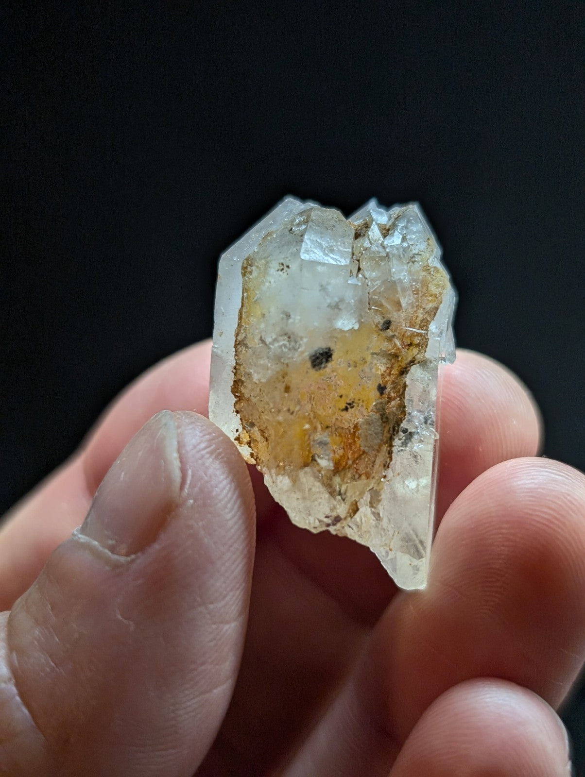 A translucent, faceted quartz crystal with a yellowish-brown internal inclusion and rough edges.