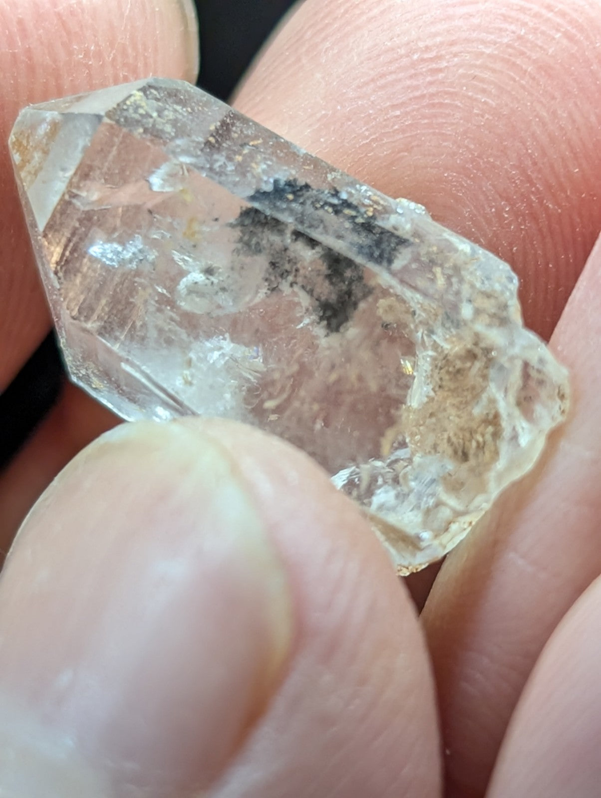 A translucent, clear quartz crystal with natural inclusions and a faceted surface.