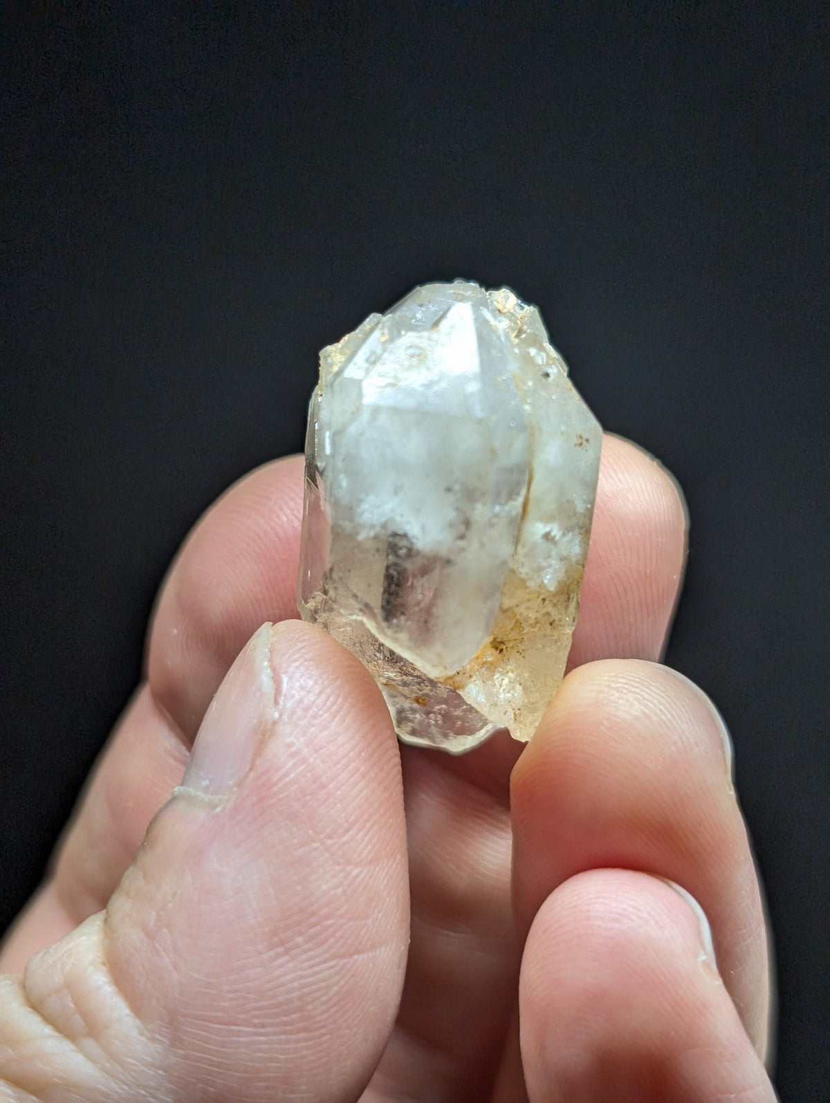 A translucent, faceted quartz crystal with a slightly cloudy appearance and subtle yellowish inclusions.
