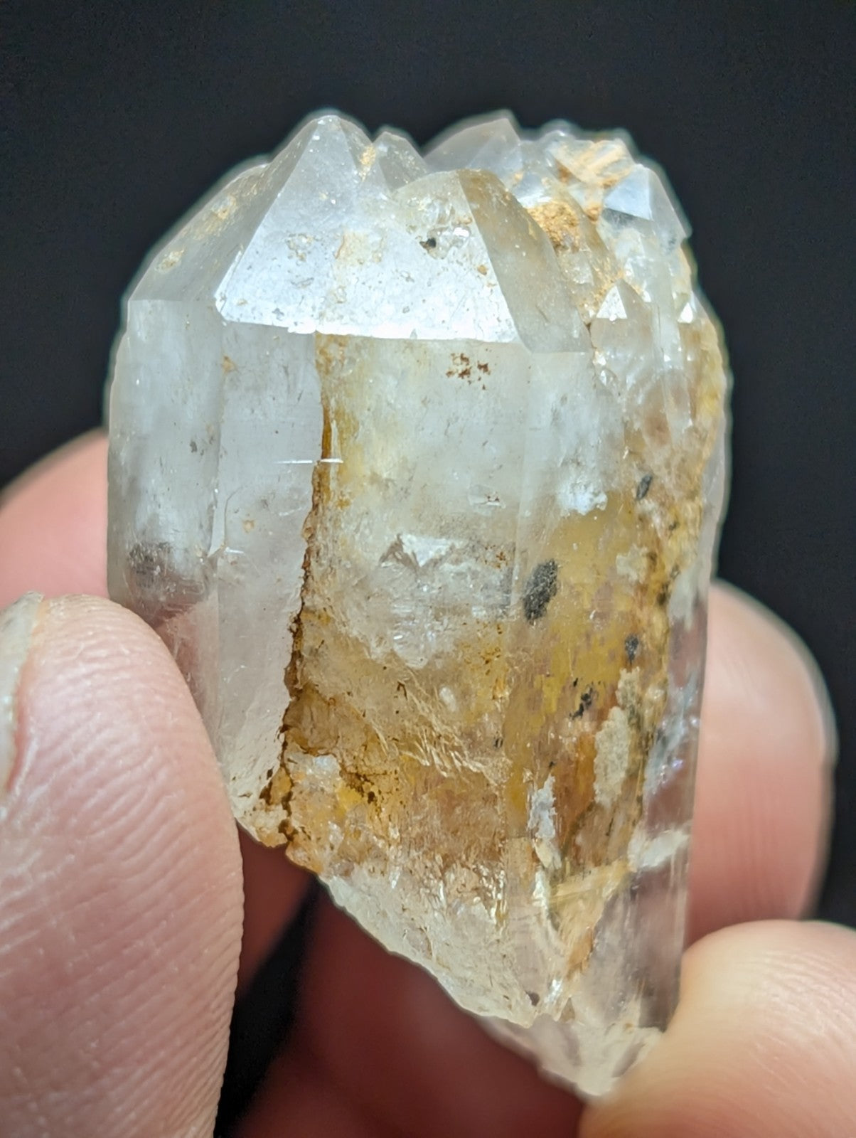 A translucent quartz crystal cluster with clear, faceted points and golden-brown mineral inclusions.