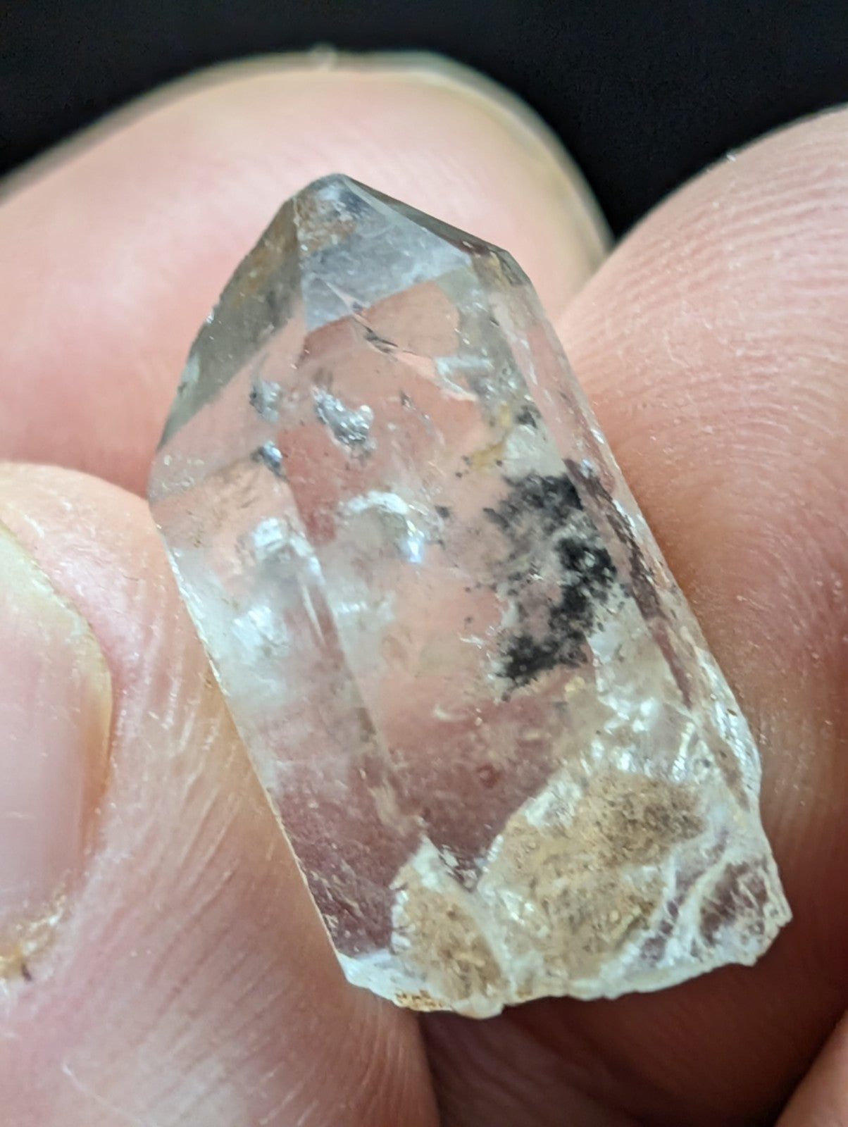 A clear quartz crystal with natural inclusions and a rough, faceted surface.