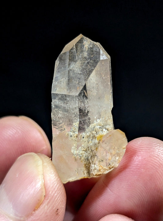 A translucent, clear quartz crystal with a pointed tip and natural inclusions.