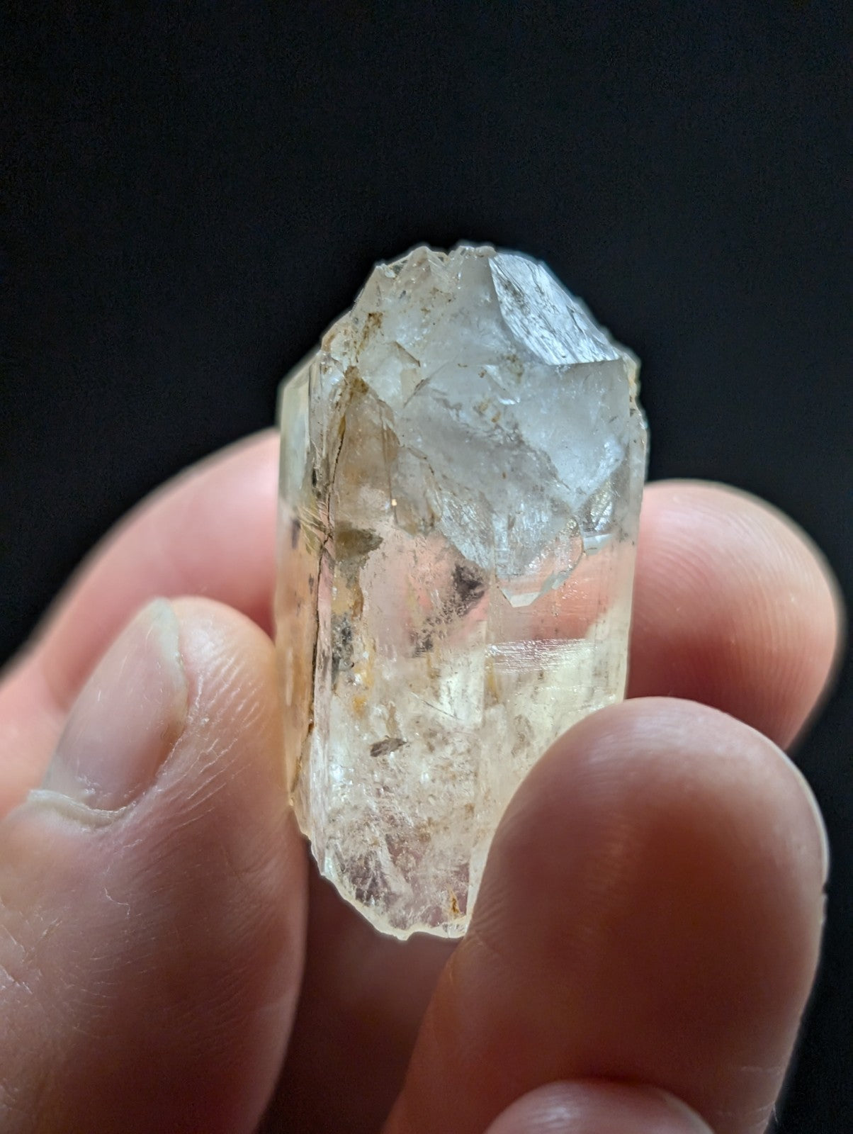 A translucent, pale yellowish quartz crystal with a rough, faceted surface and visible internal inclusions.