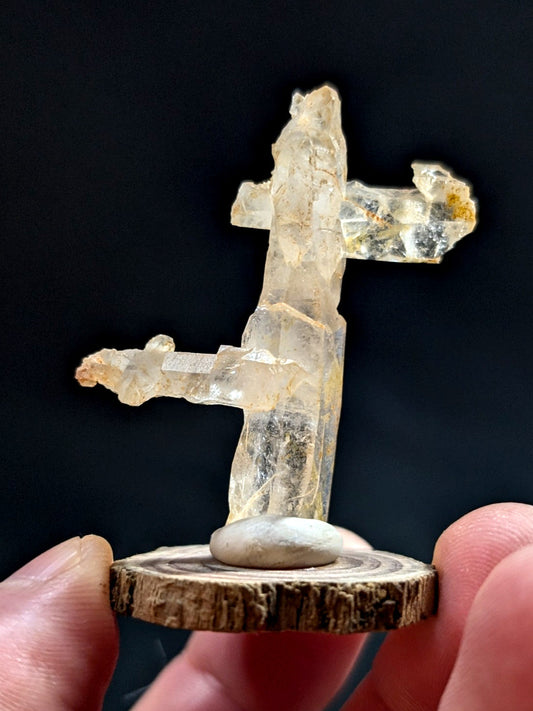 A translucent, crystalline mineral specimen with a distinct cross-like formation and subtle golden inclusions.