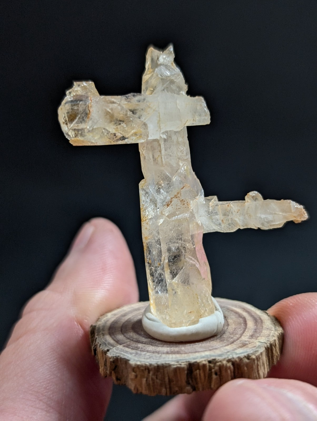 A translucent, pale yellow crystal formation shaped like a stylized figure with arms outstretched and legs apart.