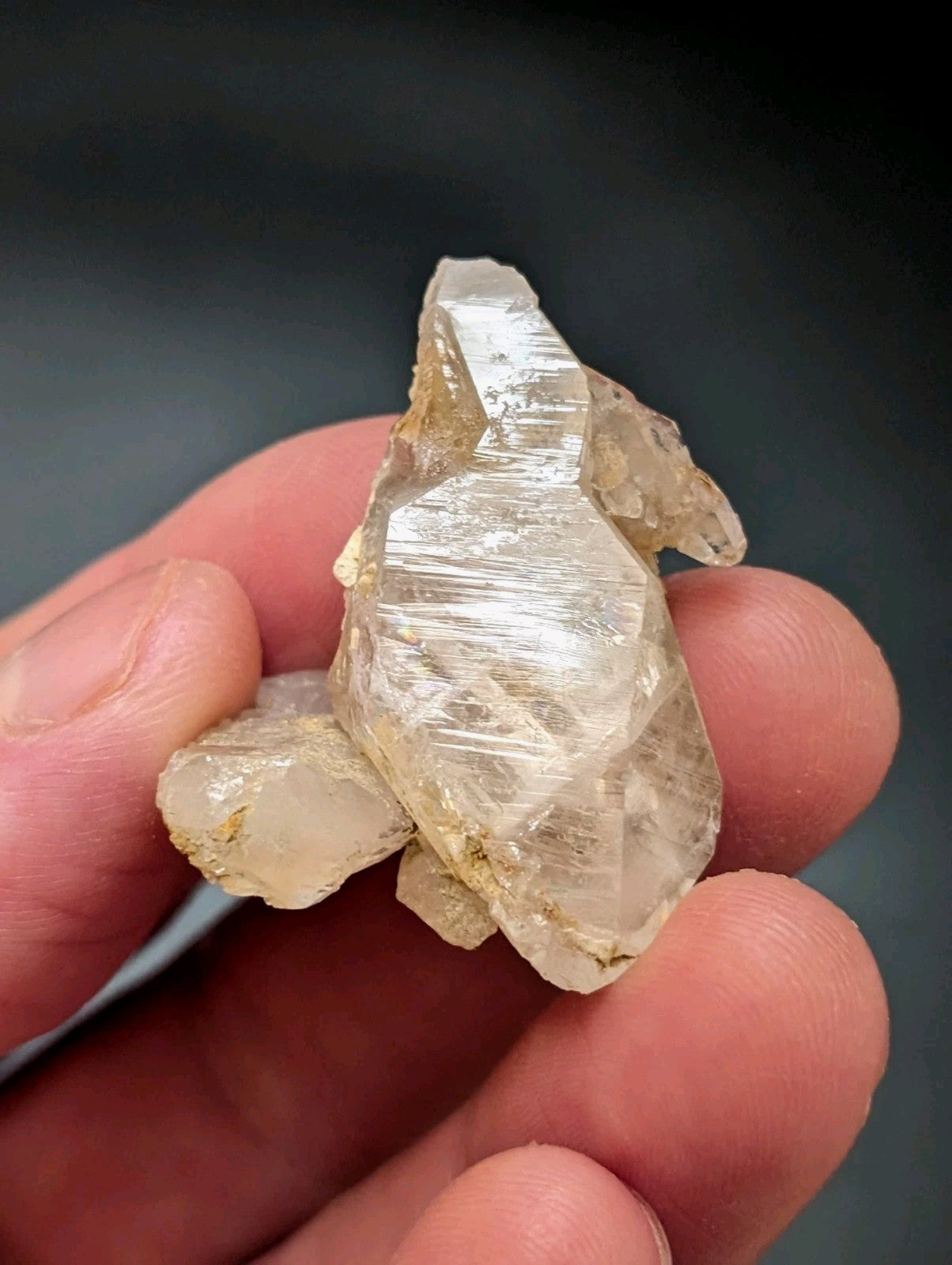 A translucent, pale quartz crystal cluster with visible internal striations and a slightly rough, earthy base.
