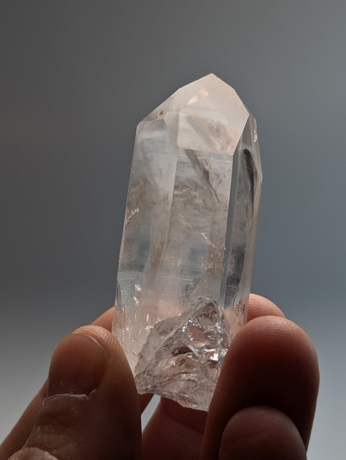 A unique clear translucent quartz crystal point with a pointed top and rough base held in hand from Arkansas USA