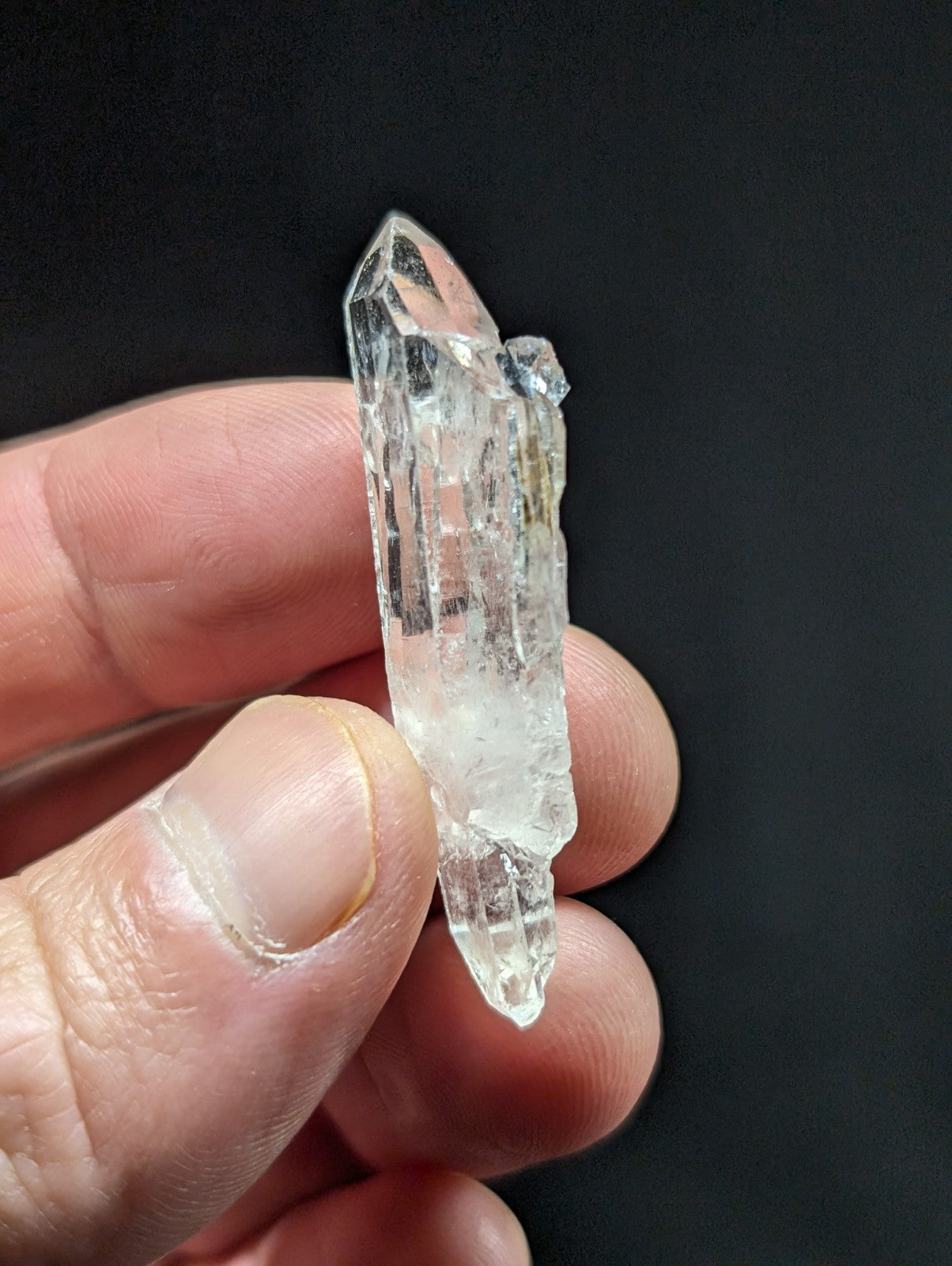 A clear, translucent quartz crystal with a pointed tip and visible internal striations.
