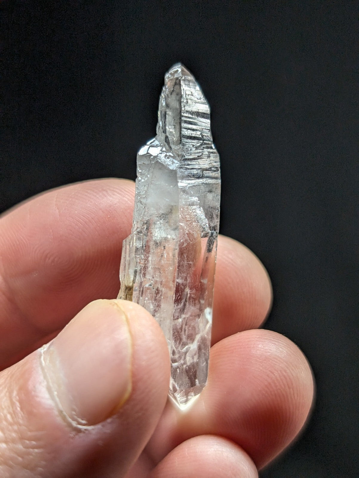 A clear, translucent quartz crystal with a pointed tip and visible internal striations.