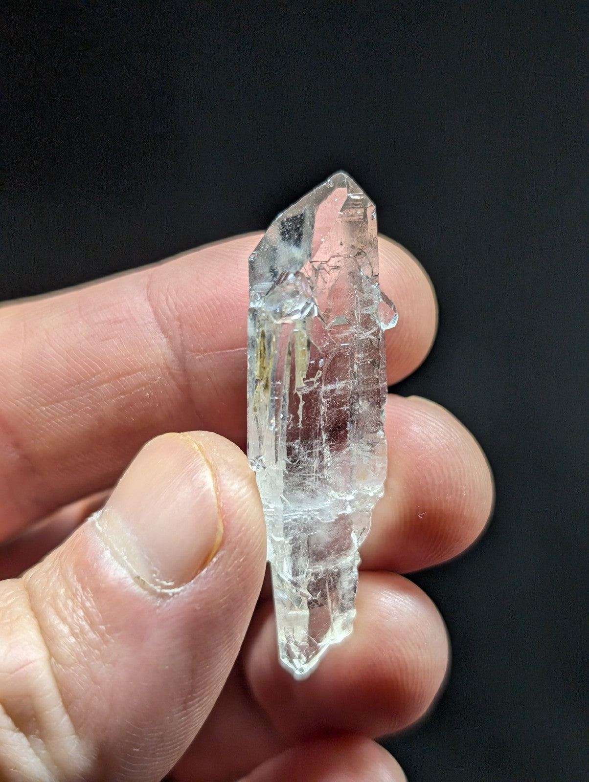 A clear, translucent quartz crystal with a pointed tip and visible internal striations.