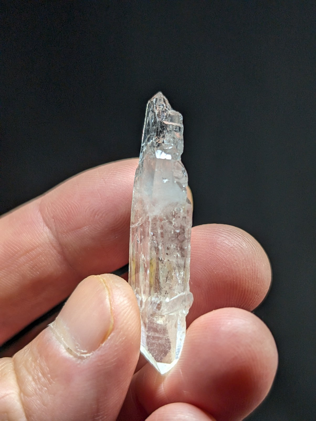 A clear, translucent quartz crystal with a pointed tip and visible internal inclusions.