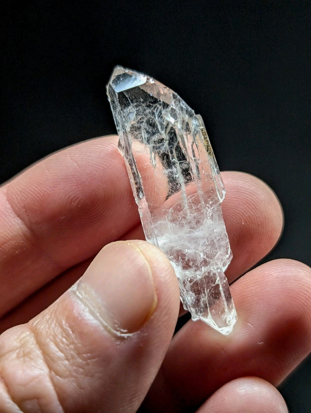 A clear, translucent quartz crystal with natural internal striations and a pointed tip.