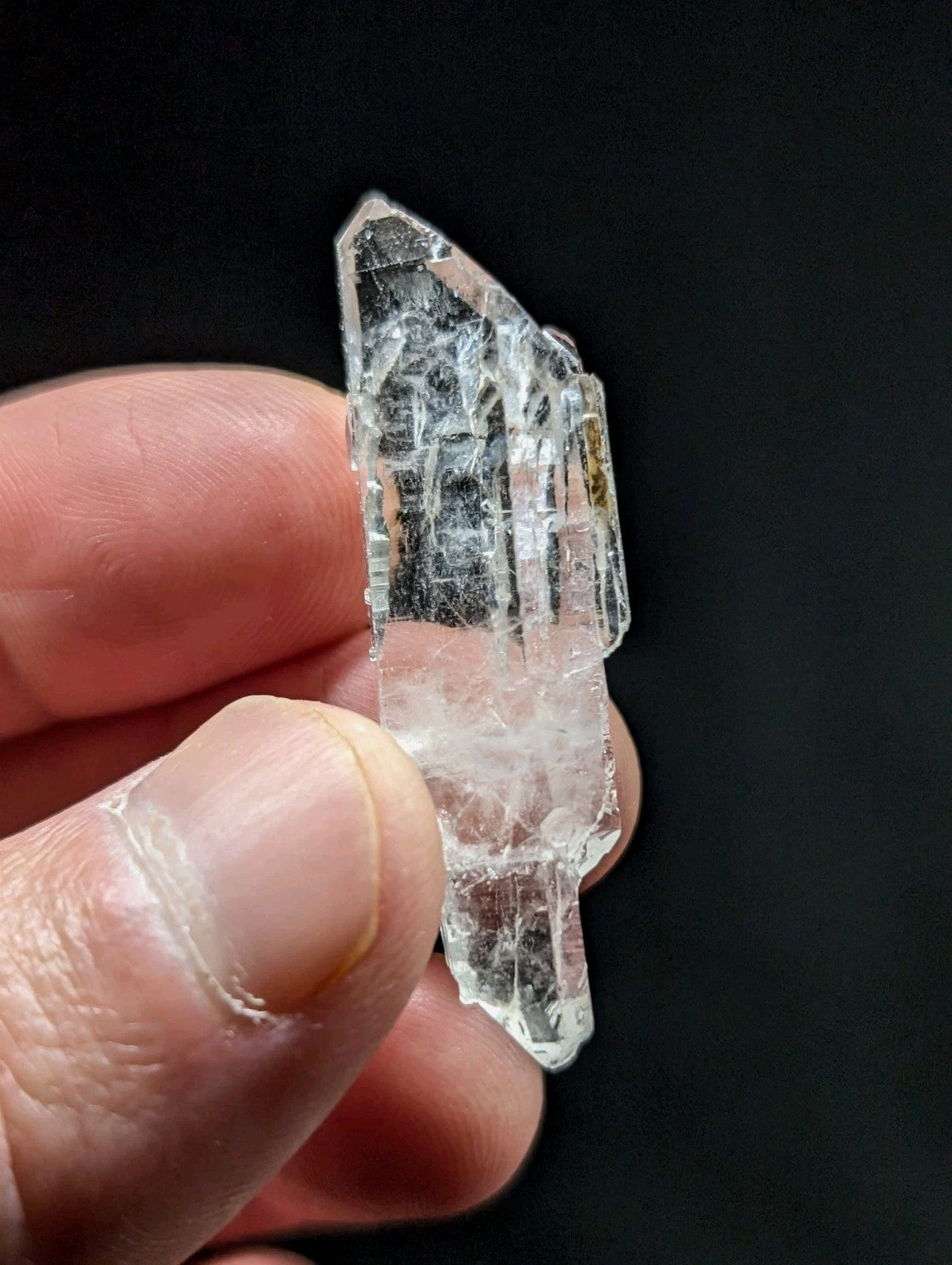 A clear, translucent quartz crystal with a pointed tip and visible internal striations.