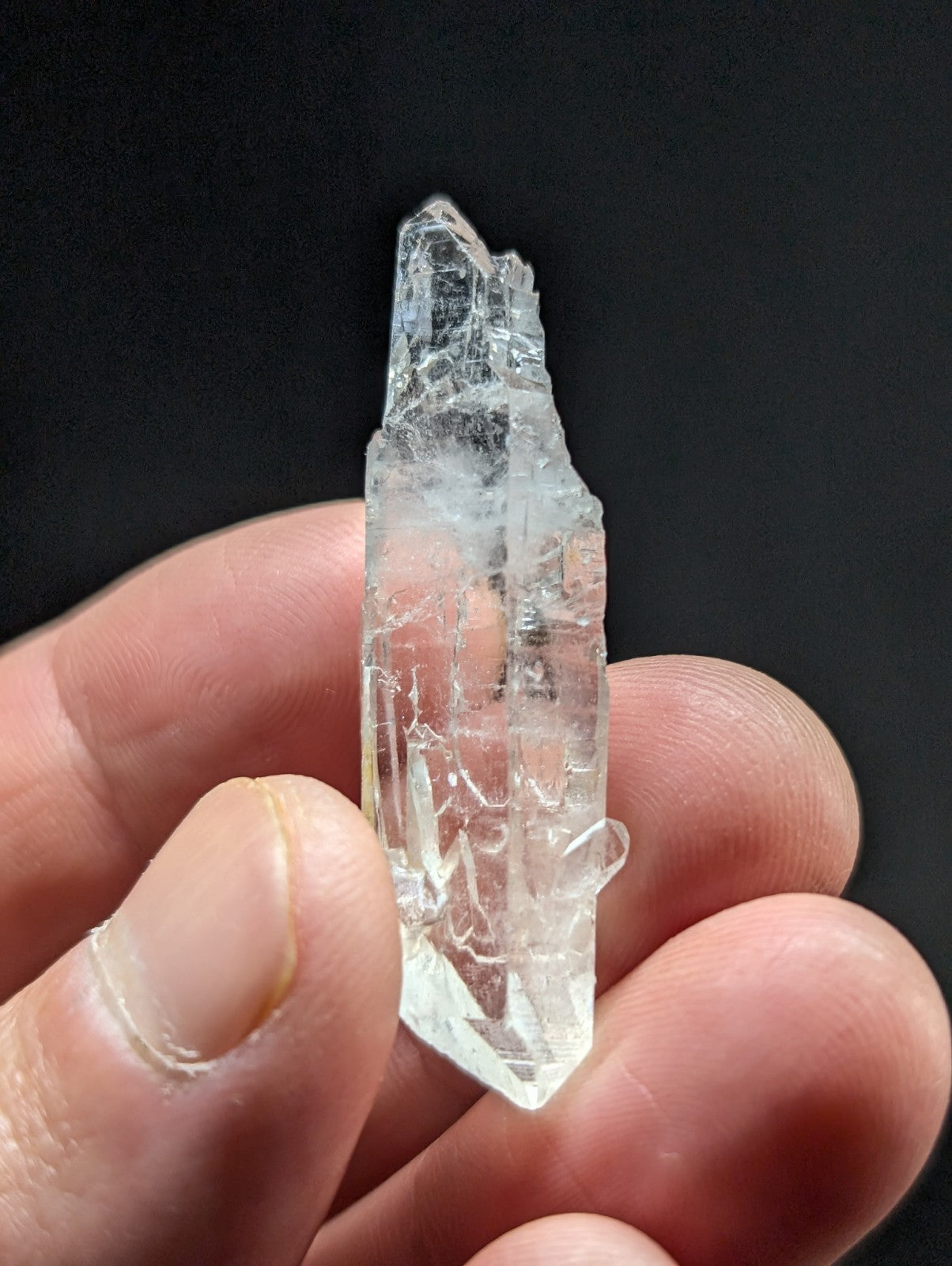 A clear, translucent quartz crystal with a pointed tip and visible internal fractures.