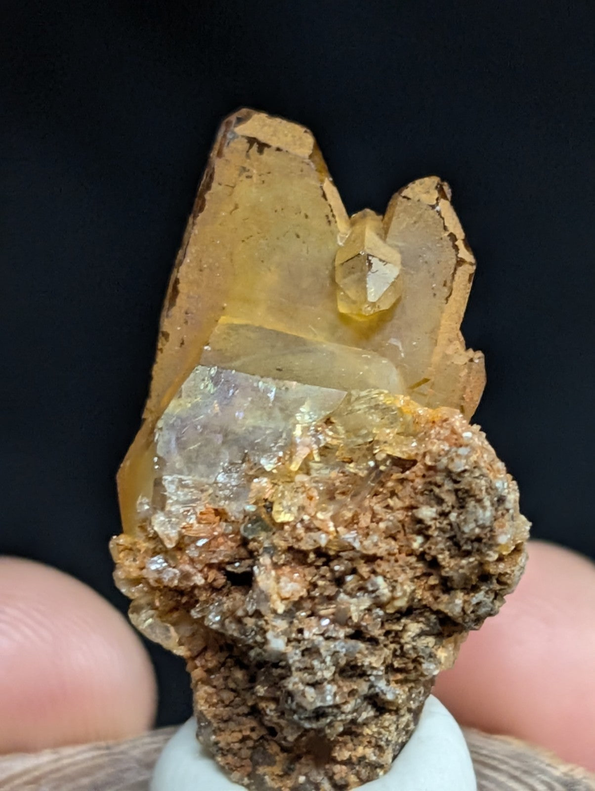 A translucent golden-yellow crystal formation with a rough, earthy brown matrix base.
