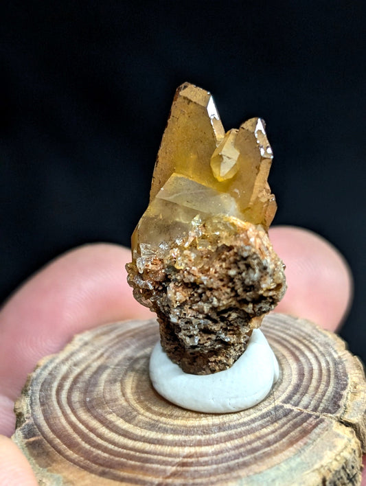 A golden-yellow citrine crystal cluster with sharp, translucent facets emerging from a rough brown matrix base.