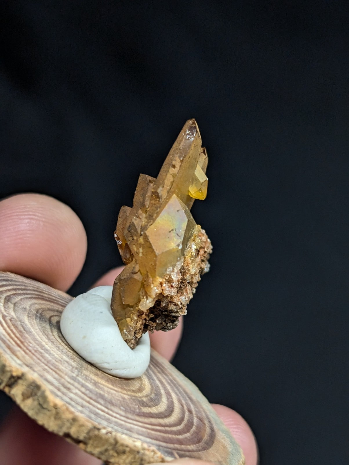 A translucent amber-colored crystal cluster with sharp, faceted points and a rougher brownish base.