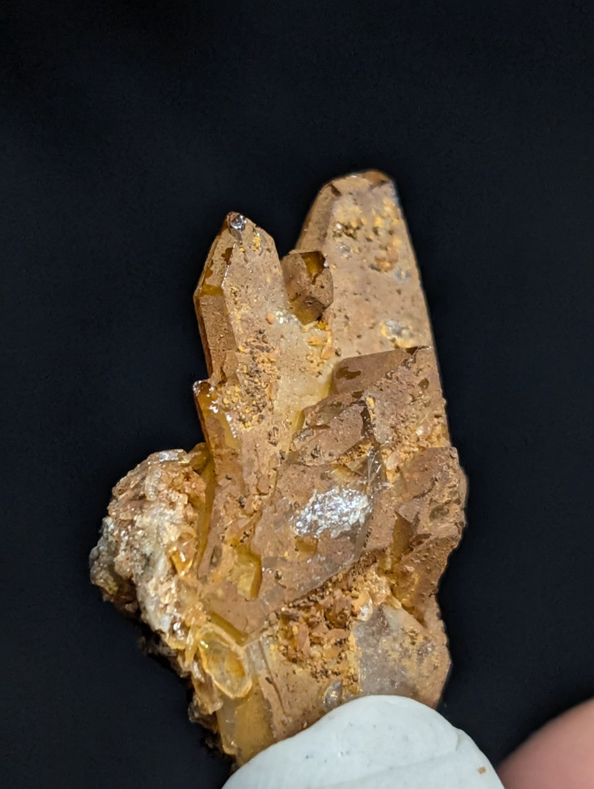 A translucent amber-colored crystal cluster with golden inclusions and a rough, earthy matrix.