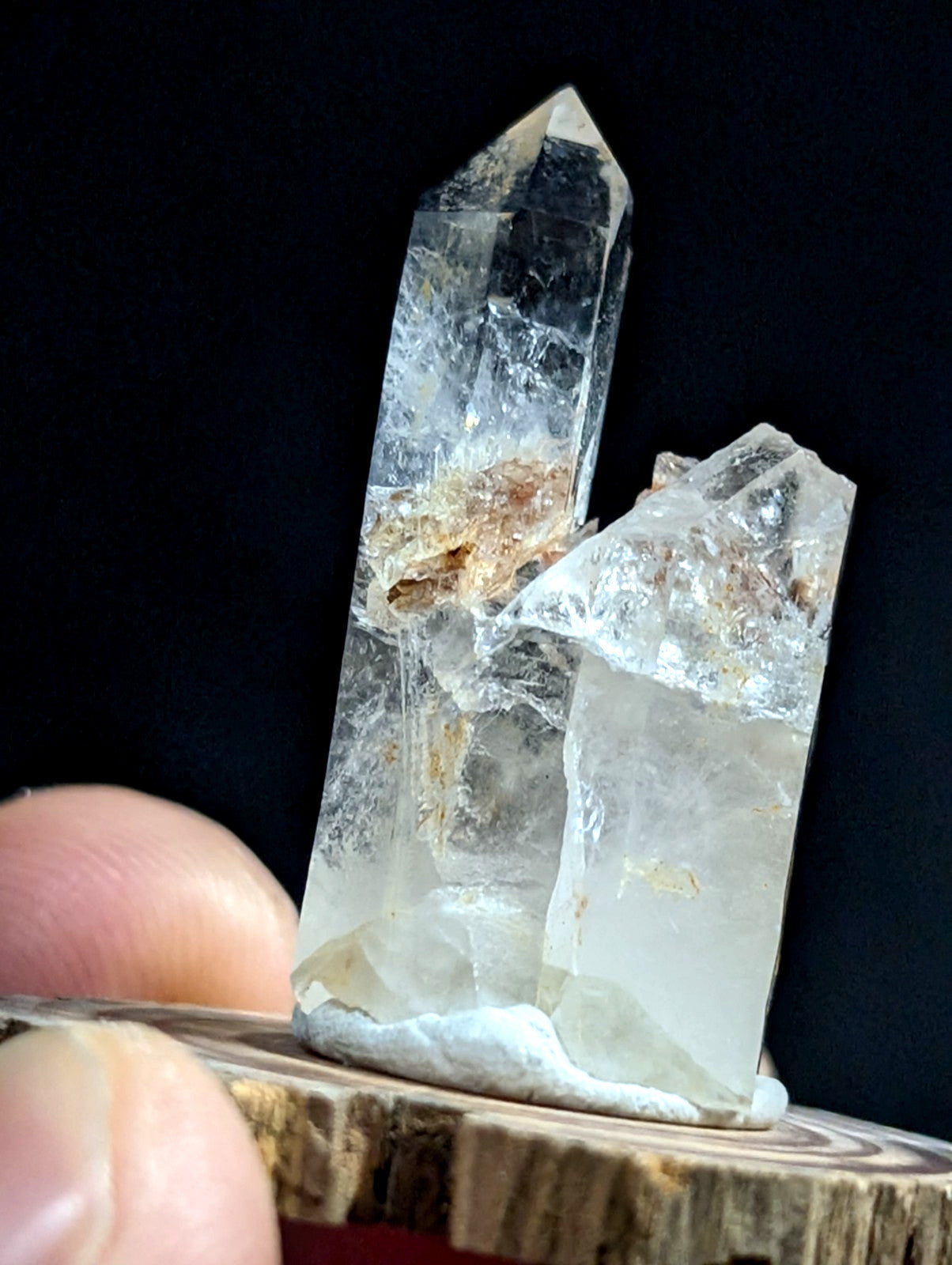 Clear quartz crystal cluster with a tall, pointed main spike and smaller adjacent crystals, featuring natural inclusions of brownish mineral deposits.