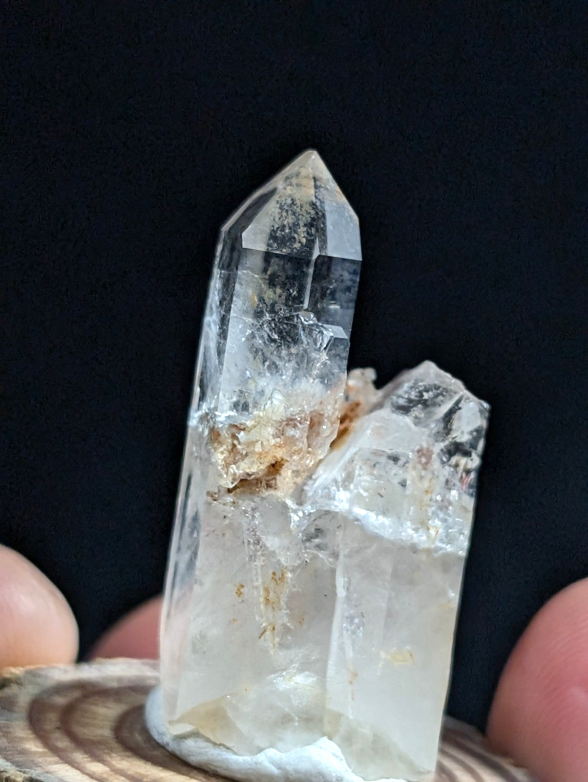 A clear quartz crystal cluster with a tall, pointed main spike and smaller adjacent crystals, featuring natural inclusions and subtle golden-brown mineral deposits.