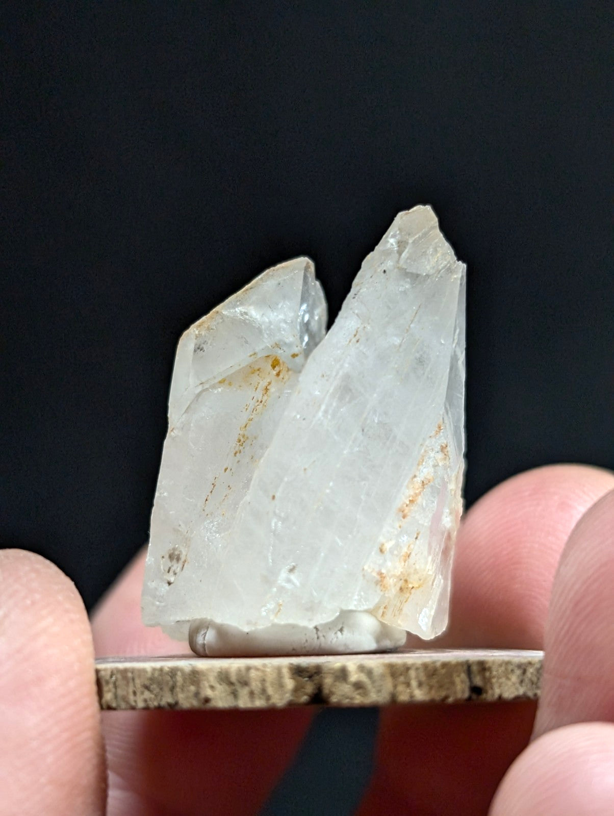 A translucent, pale quartz crystal cluster with subtle golden inclusions and sharp, angular facets.