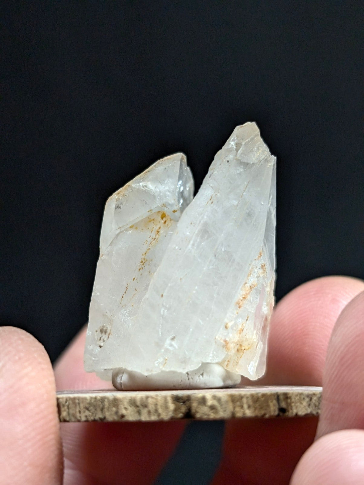 A translucent, pale quartz crystal cluster with subtle golden inclusions and sharp, angular facets.