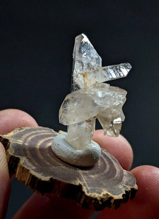 A clear quartz crystal cluster with sharp, translucent facets and a natural, earthy base.