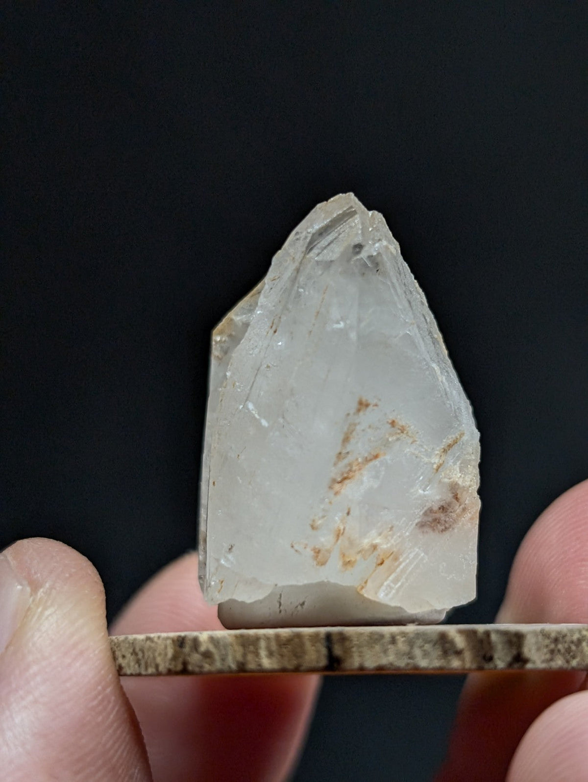 A translucent, pale quartz crystal with natural inclusions and a pointed tip.