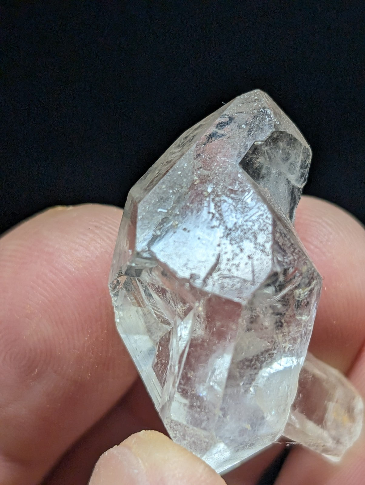A clear, faceted quartz crystal with natural inclusions and a pointed tip.