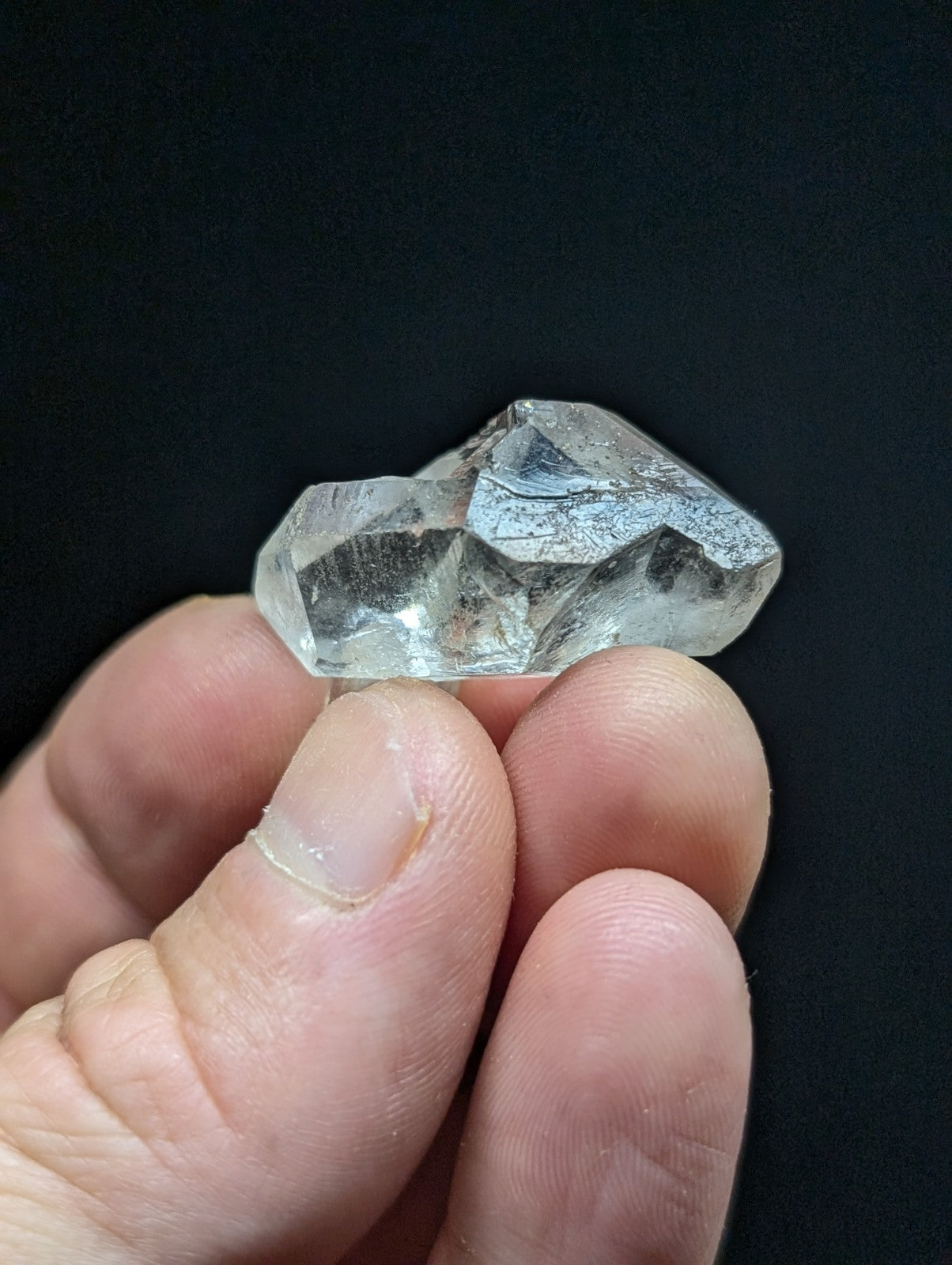 A clear, faceted quartz crystal with a slightly cloudy appearance and visible internal inclusions.